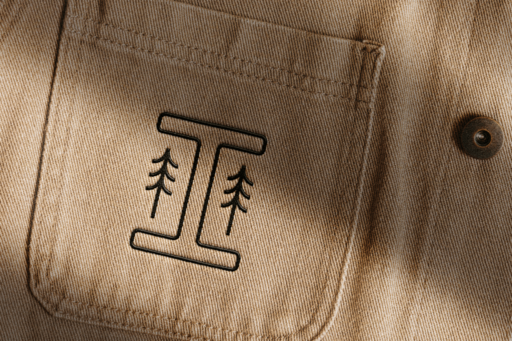 The pocket of a tan shirt with a tree on it. Embroidered-Badge Ironwood Edited