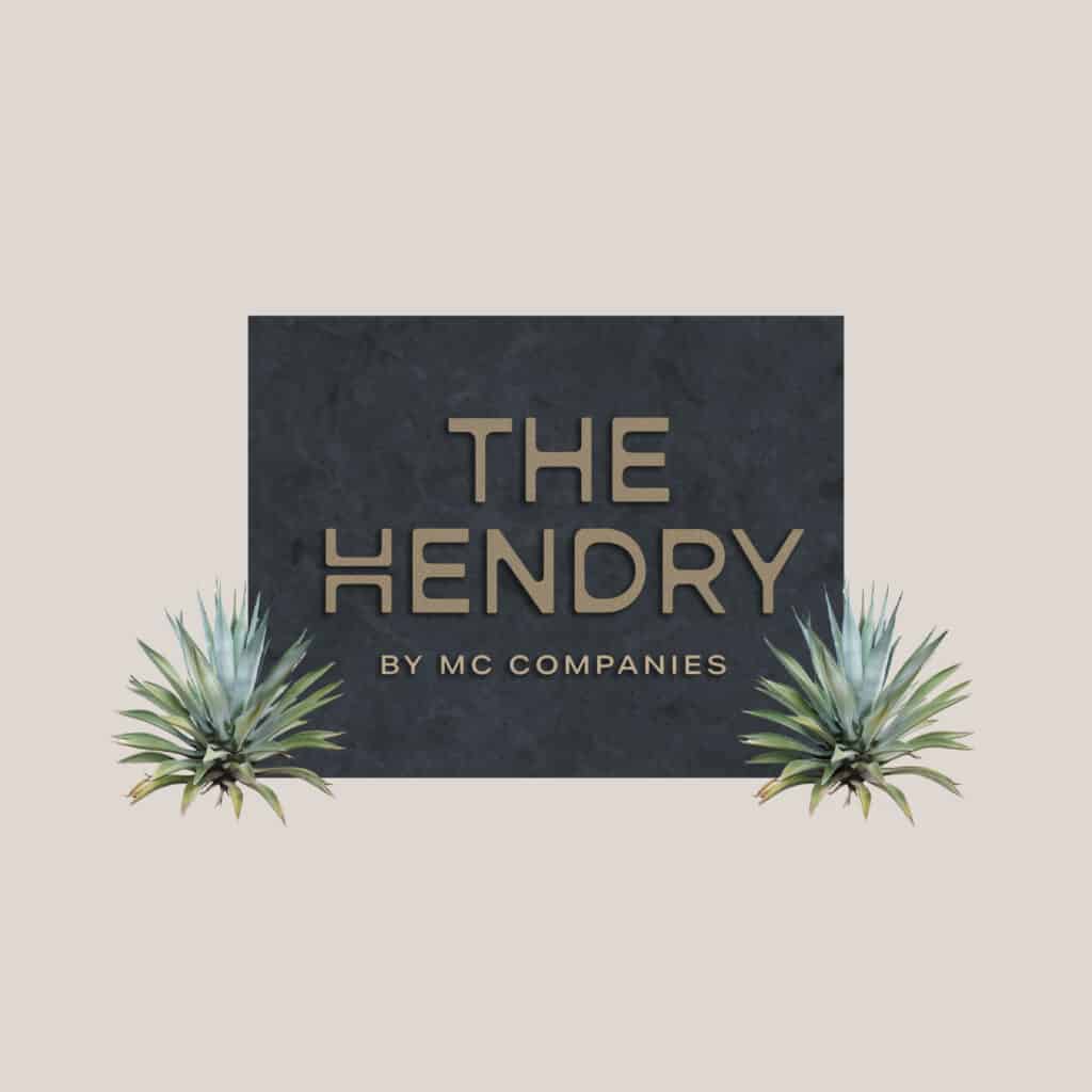 Text reading "THE HENDRY by MC COMPANIES" on a dark background with two small green plants at the bottom corners.